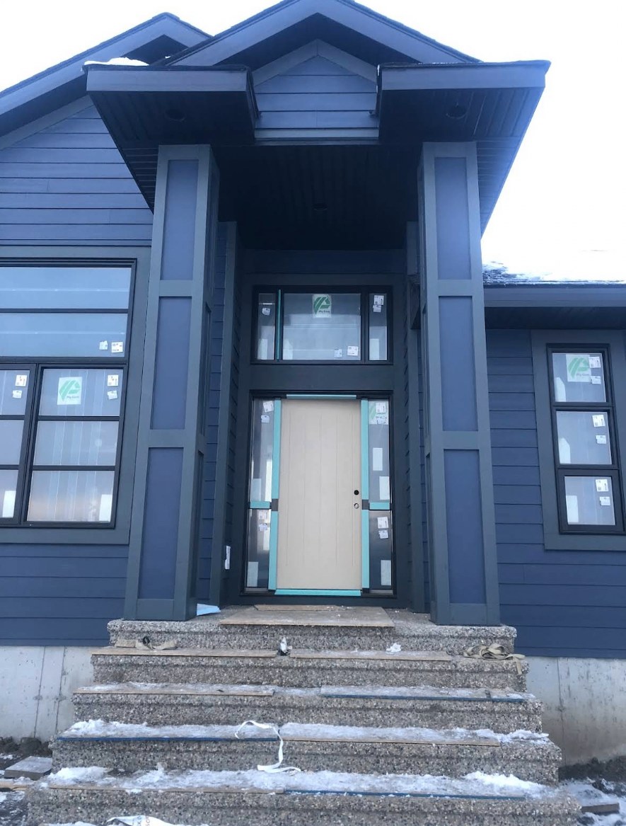 Modern home entrance with a vertical western red cedar slat feature wall beside a black steel door