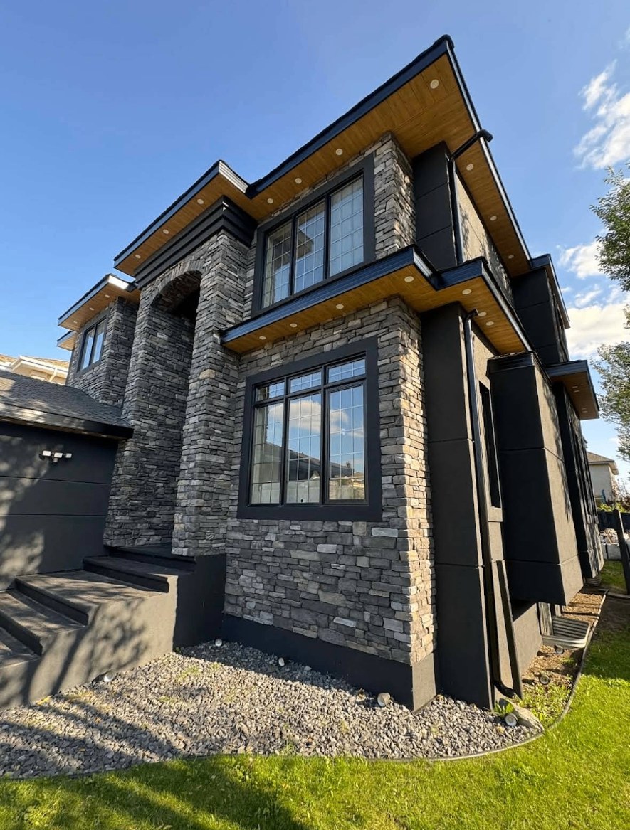 Modern two-storey Edmonton home at dusk clad in charcoal Hardie board siding with vertical cedar accent panels